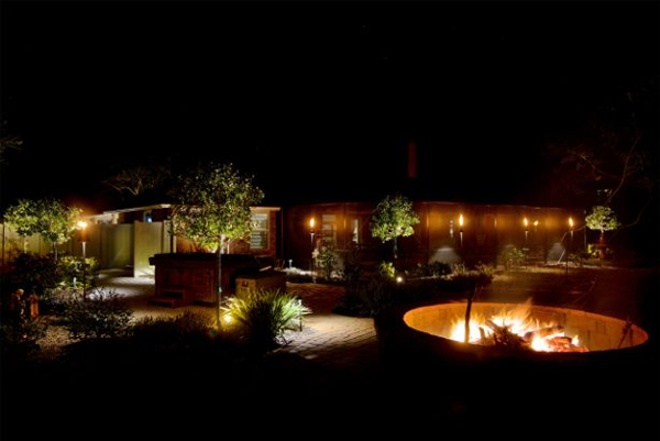 backyard with outdoor lighting, trees, and a fire pit