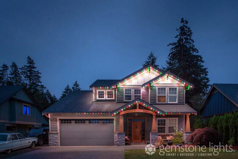 Gemstone Lights on a two story home with evergreen tree behind it