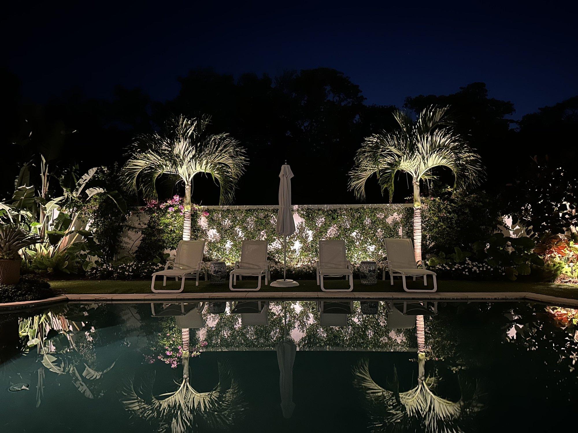 Pool and palms reflecting softly in the water at a South Florida waterfront home at night