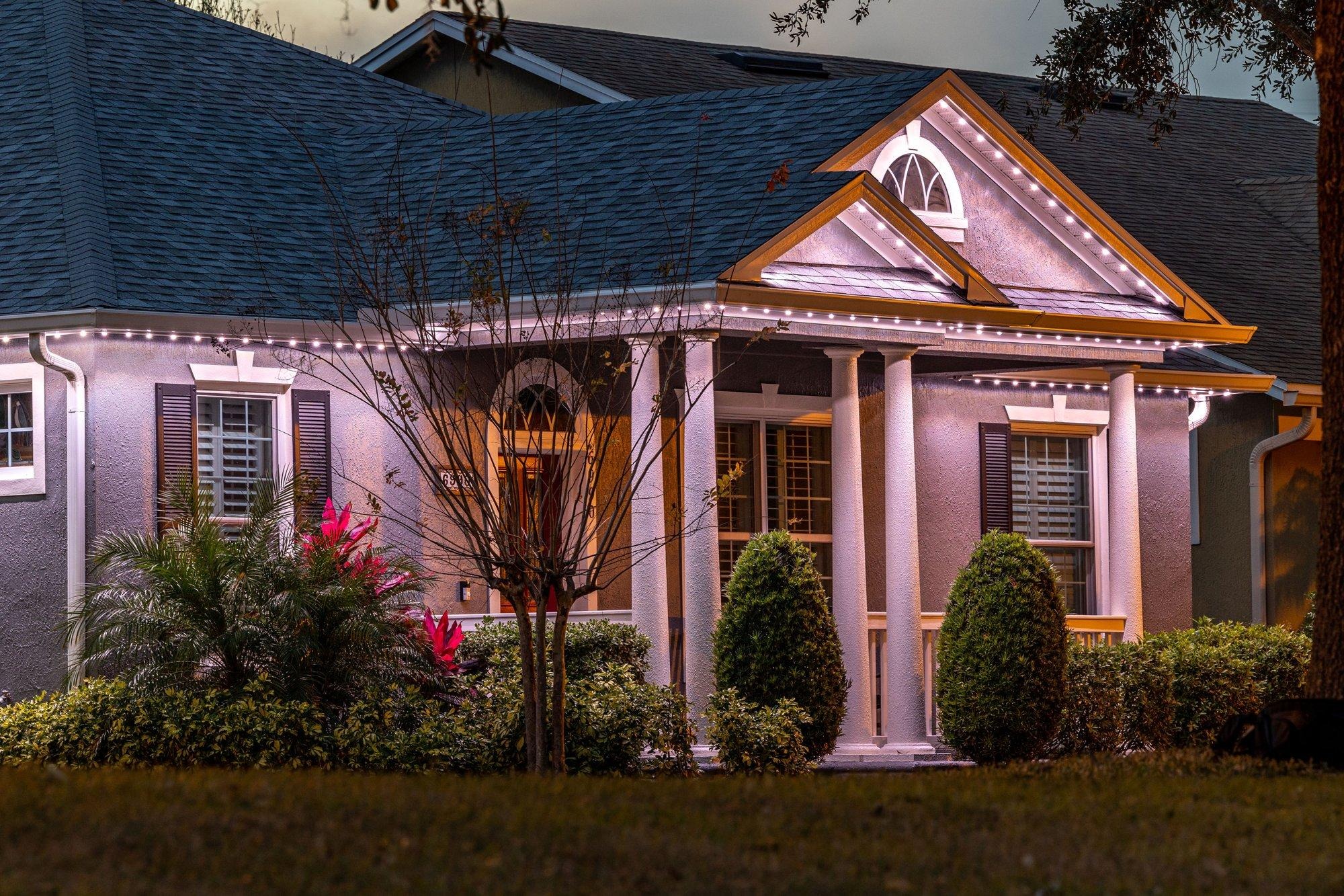 Coastal home glowing in elegant warm white permanent roofline lighting