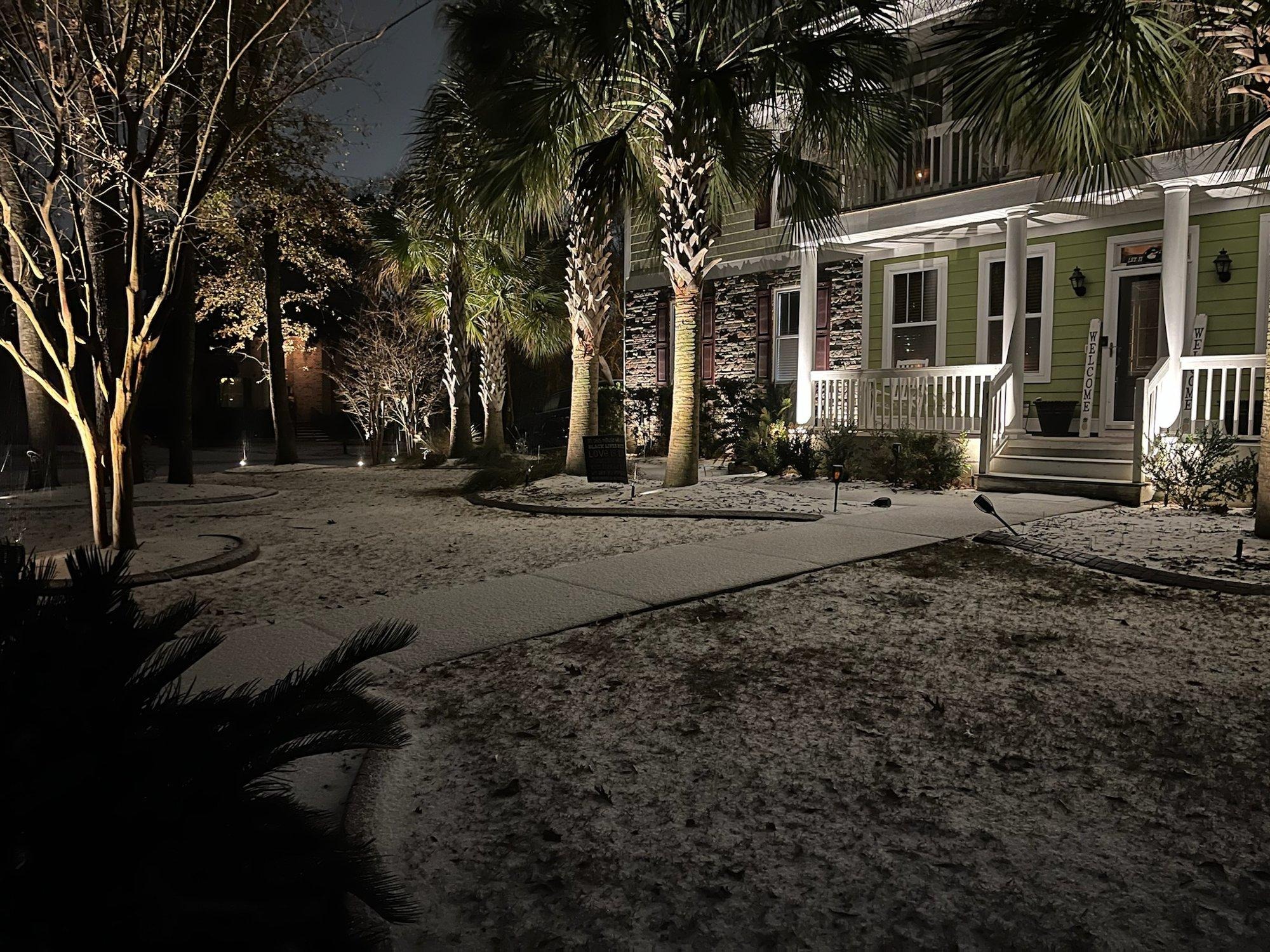 Lowcountry home with landscape lighting glowing during a rare Charleston snowfall