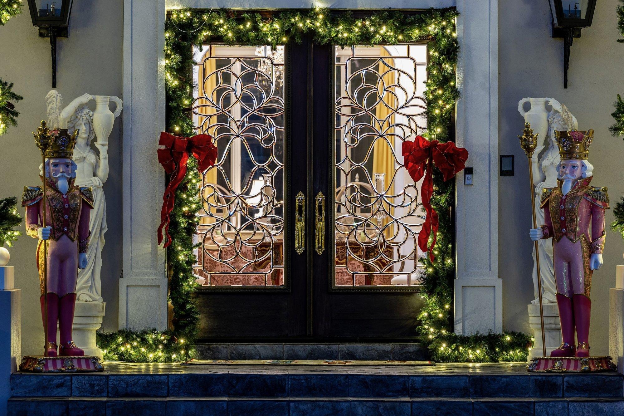 Front double doors framed in lit garland with red bows and nutcracker figures standing guard