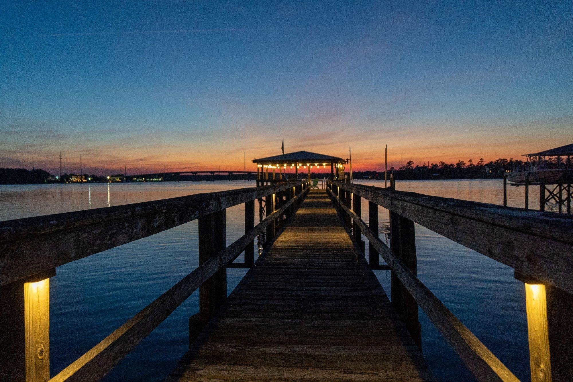 Wooden pier stretching over the water at sunset with softly glowing post lights