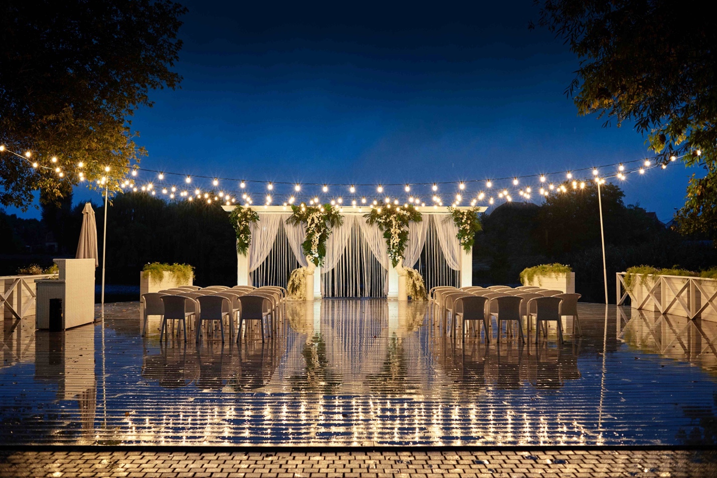 A pool with lights and a white structure with chairs and tables

Description automatically generated with medium confidence