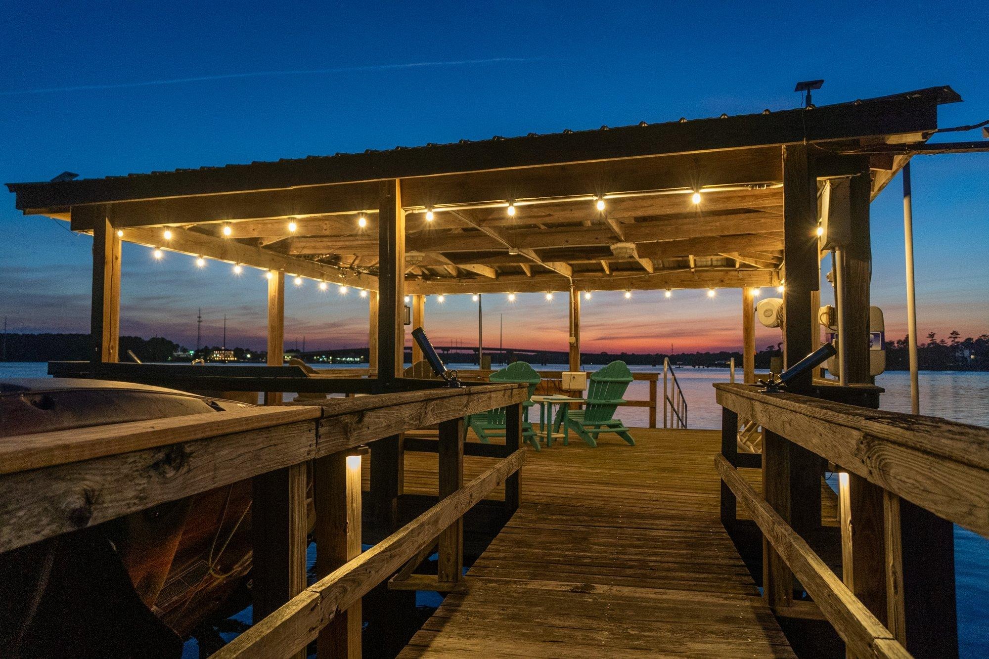 Covered dock with string lights glowing above the water at sunset in the Lowcountry