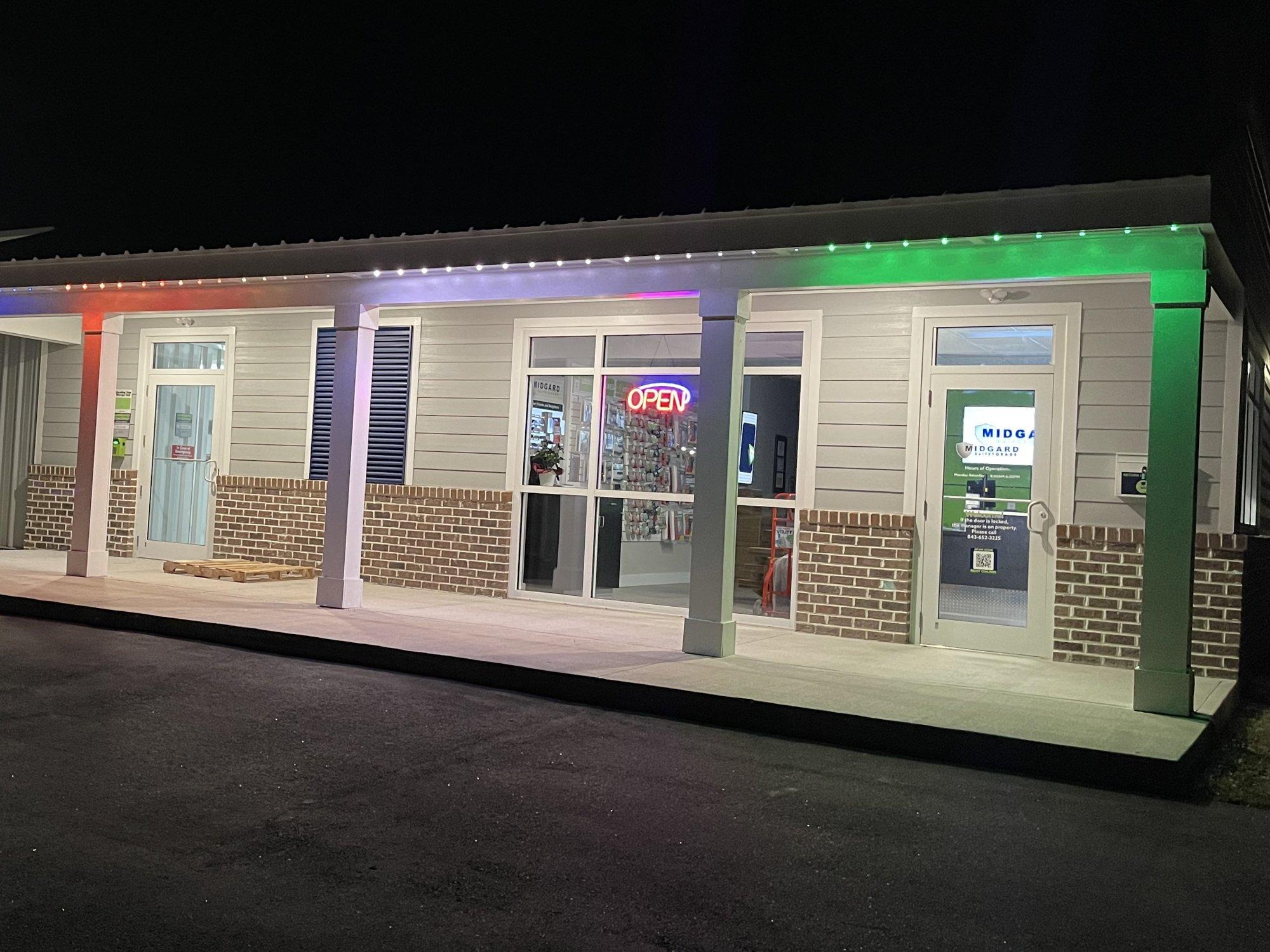 Commercial building with permanent roofline lighting glowing in red, white, blue, and green along its covered walkway