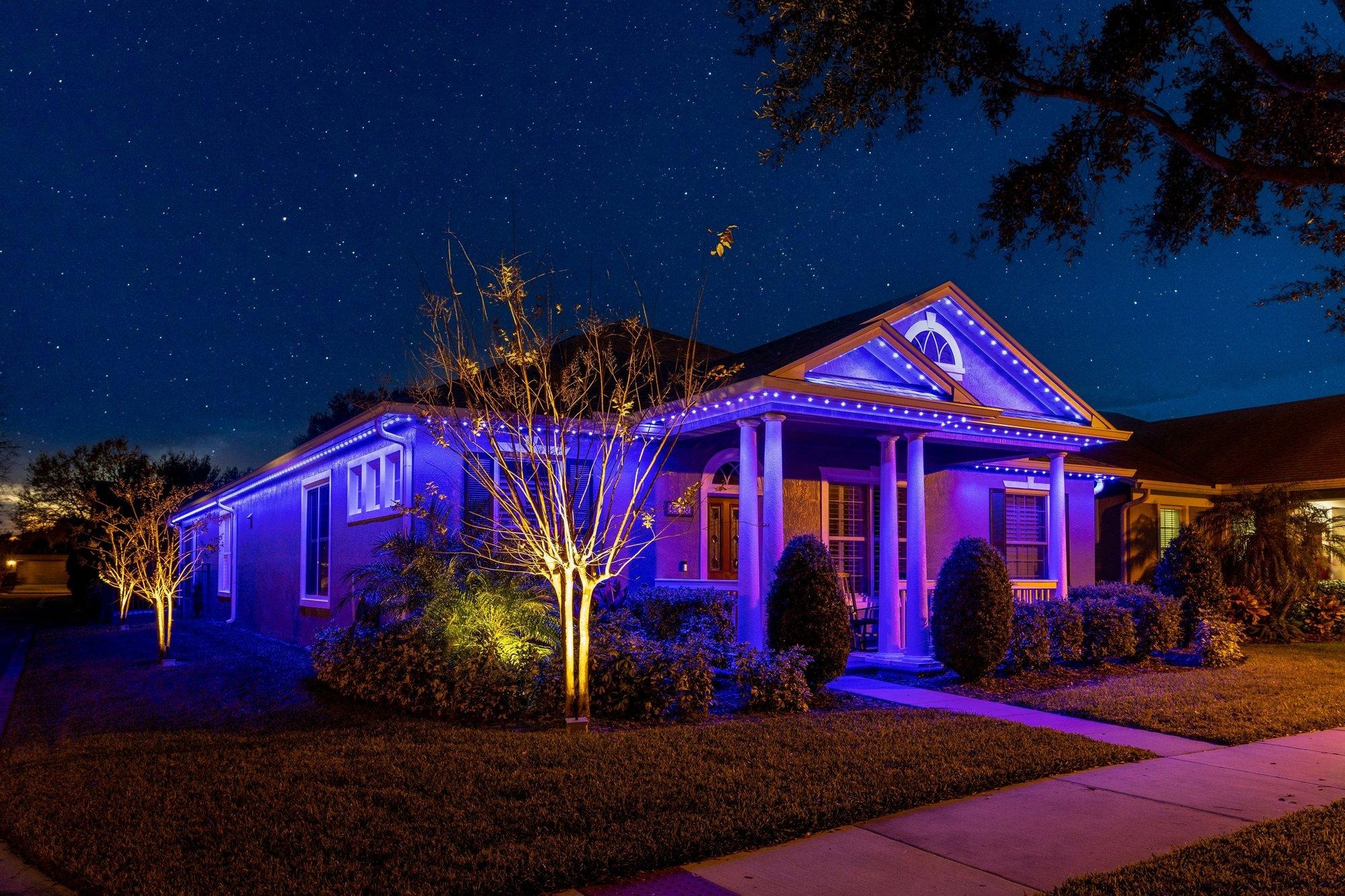Permanent lighting set to a rich coastal blue on a Florida home with palms