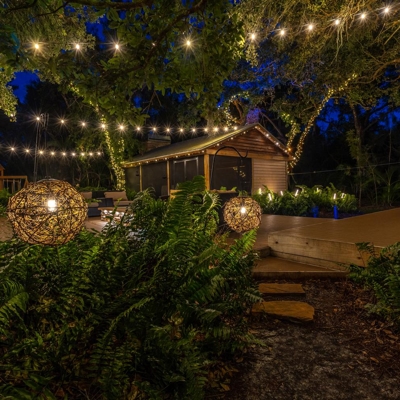 Bistro lights and globe lights create a charming atmosphere in this backyard after dark in Sarasota, Photo