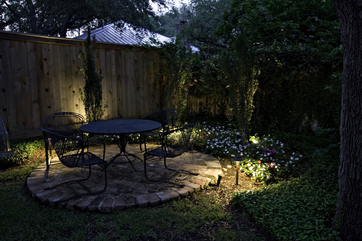backyard landscape, trees, and patio illuminated by OLP lighting