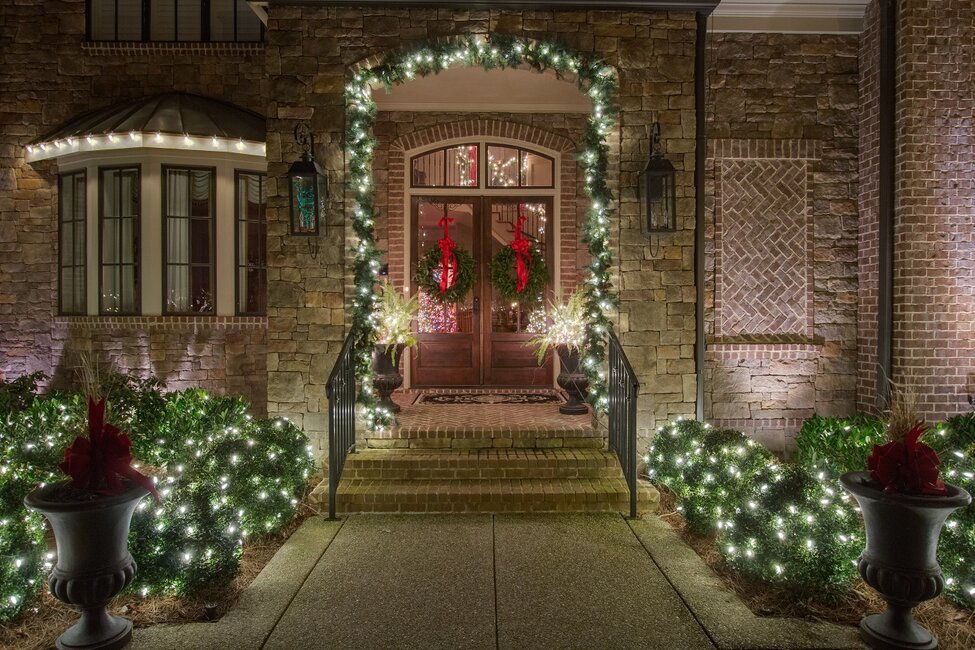 Front door entry way decorated with Christmas lights and decor