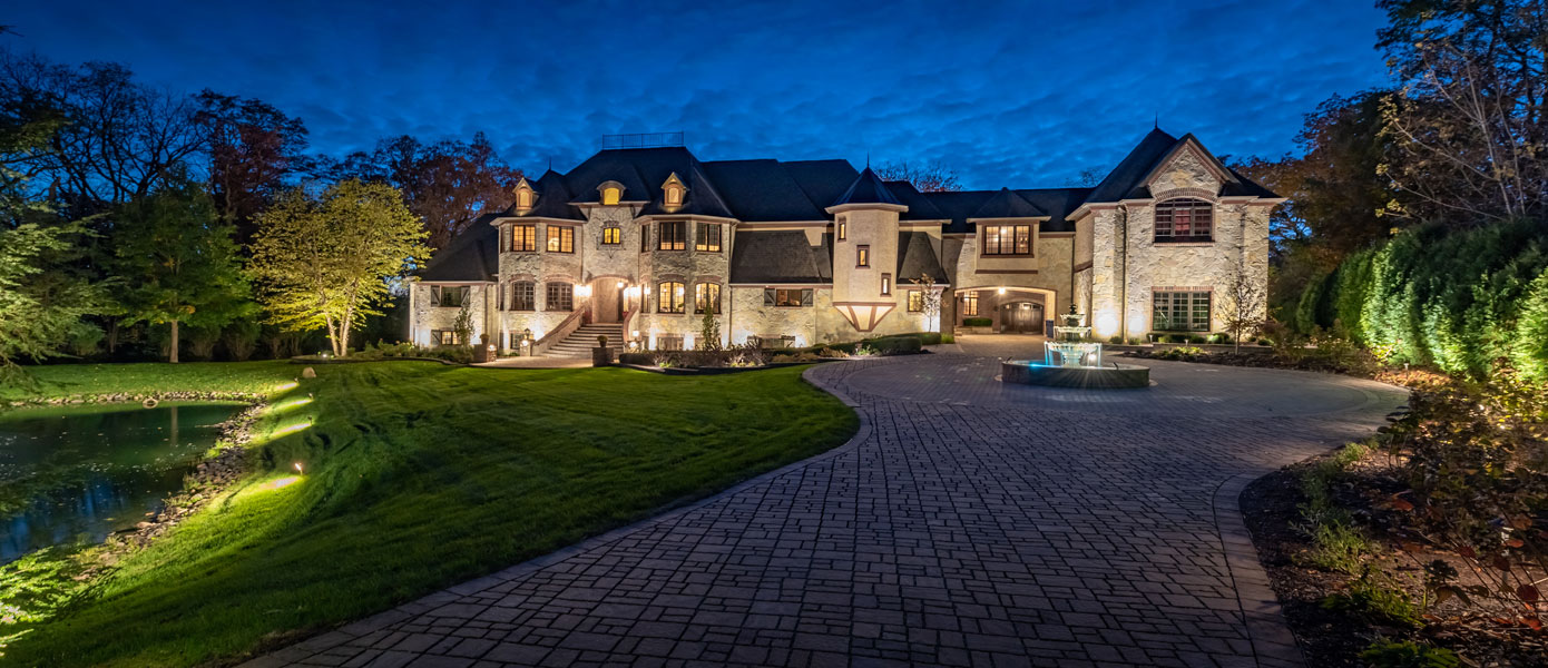 large white home with circle driveway lit up by outdoor lighting