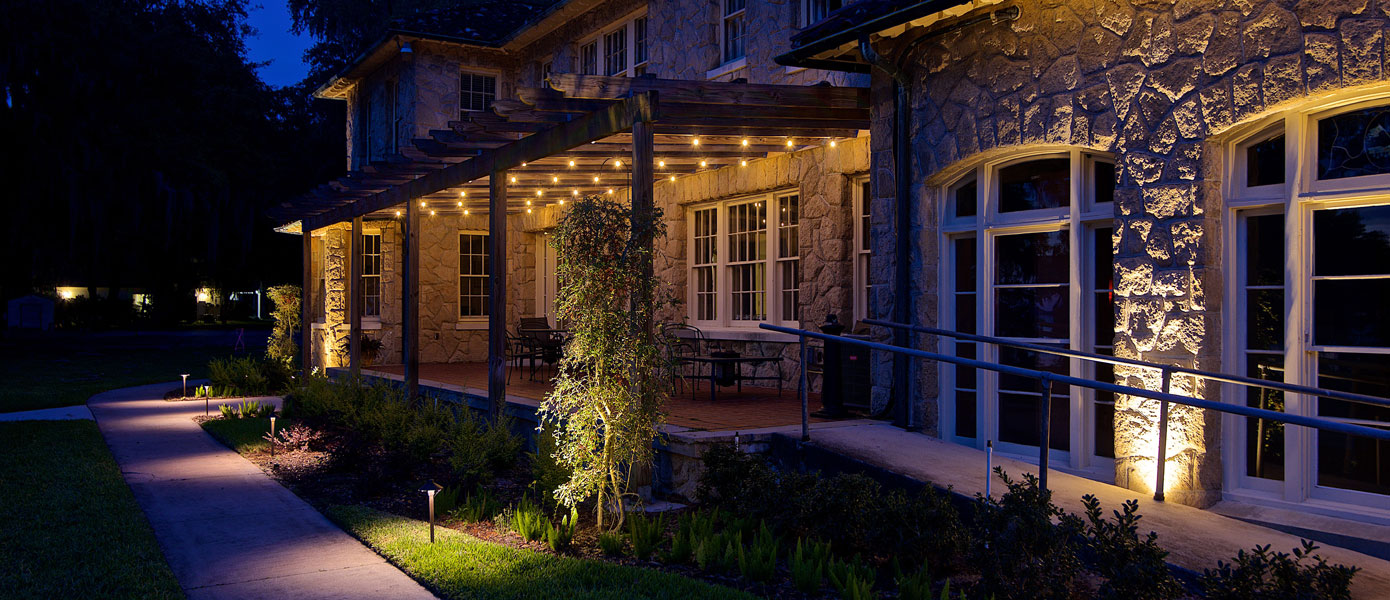 ramp up to a covered patio with landscape lighting and plants