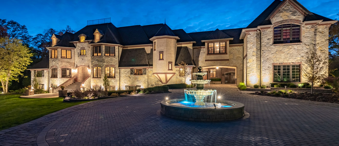 large house with outdoor lighting and fountain 