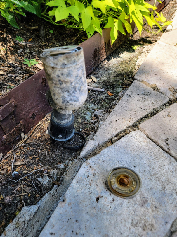"A close-up view of a severely corroded and pitted aluminum landscape light fixture from a Katy, Texas soil bed, illustrating the devastating effect of humidity 'wicking' that destroys transformers."