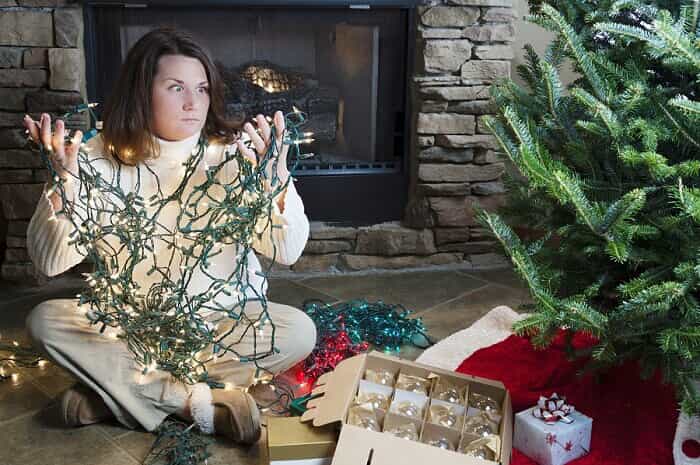 Frustrated woman holding tangled Christmas lights