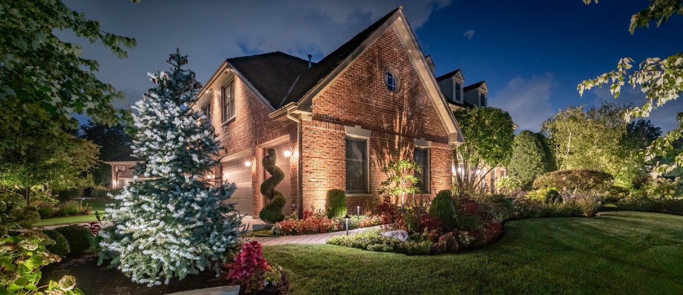 side of home with landscape lighting around plant landscaping