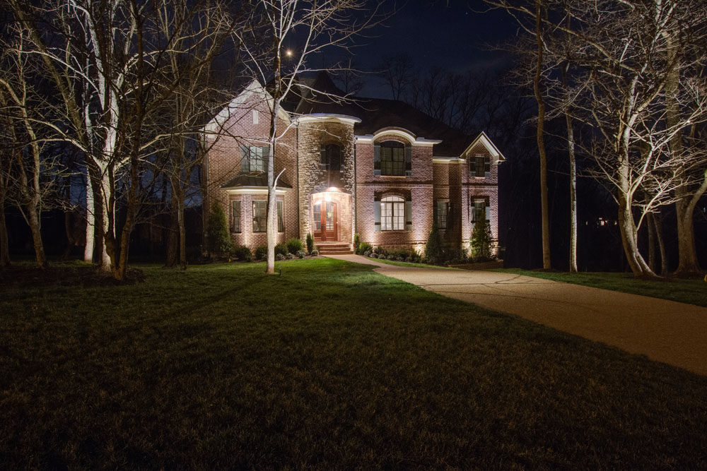 Front yard and driveway leading up to a home, all with special lighting