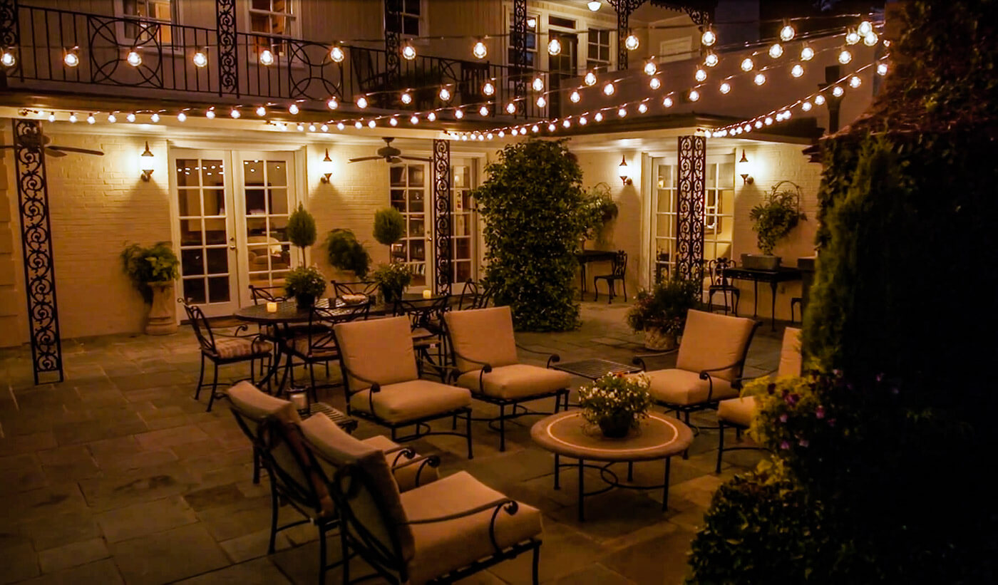 Outdoor patio with lots of chairs and a table and festive lighting