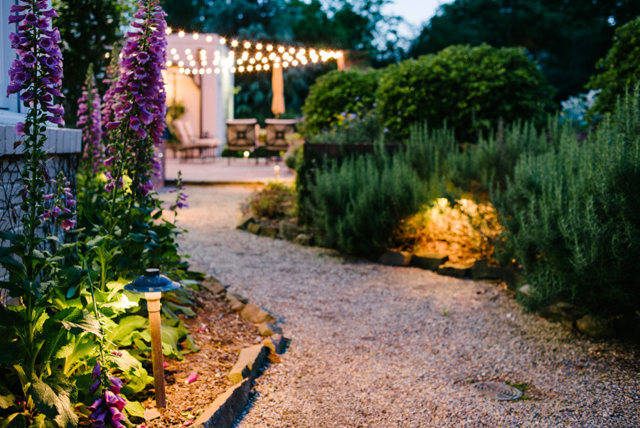 Rock pathway through flowers and other greenery, all lit by pathway lighting