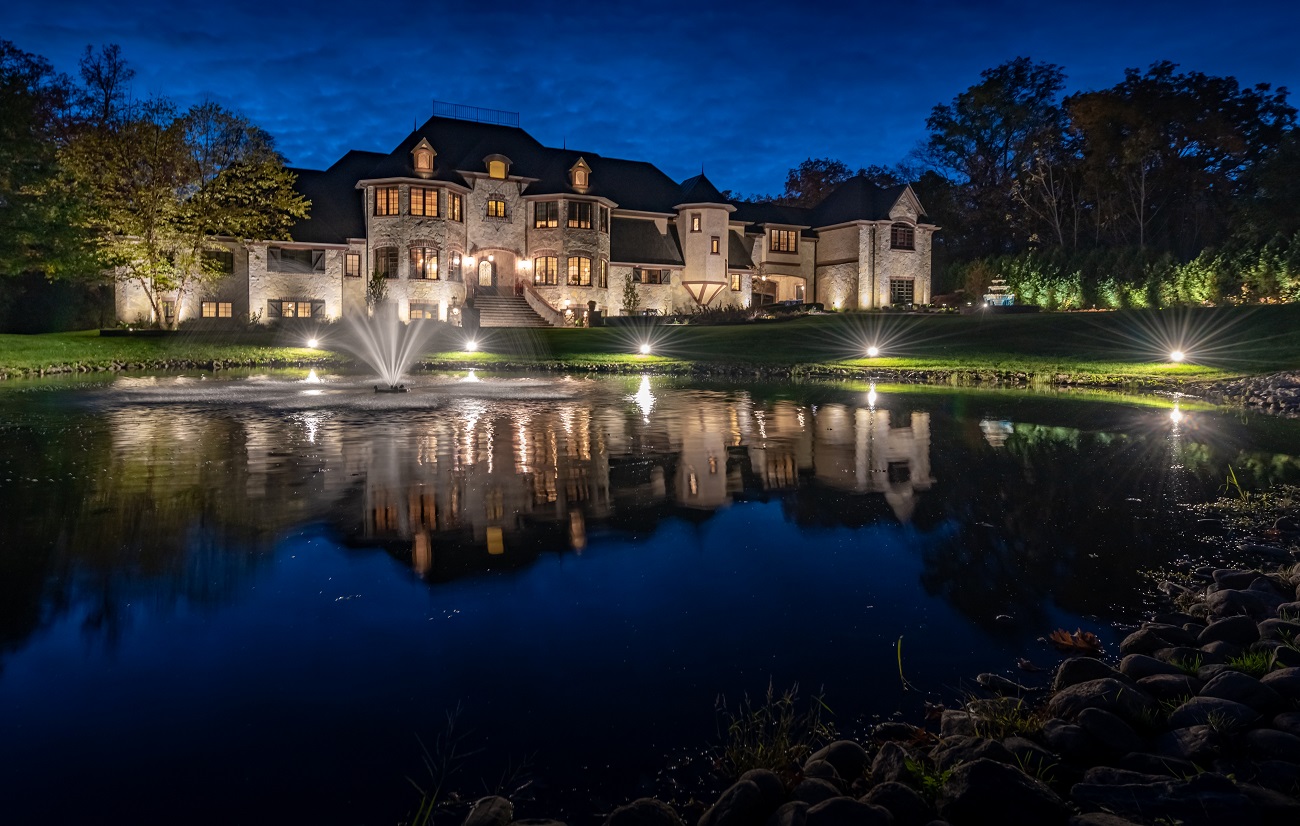 large home with pond, fountain and outdoor lighting