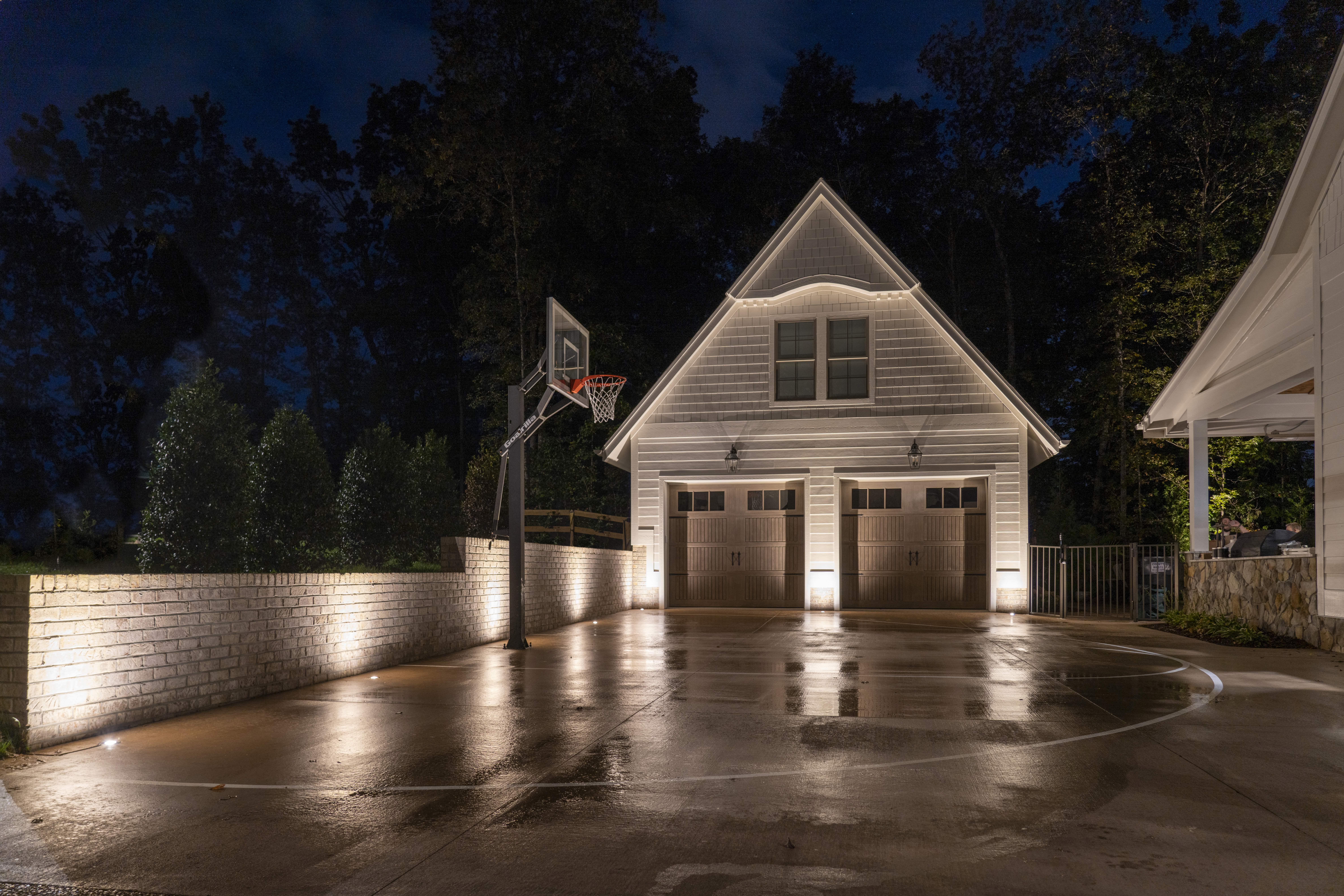 A basketball court with a garage and a basketball hoopDescription automatically generated