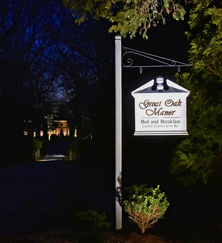 outdoor bed and breakfast sign that is lit up by spotlight