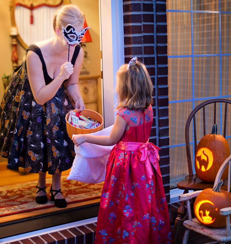 woman holding a bowl of candy for young girl trick or treating