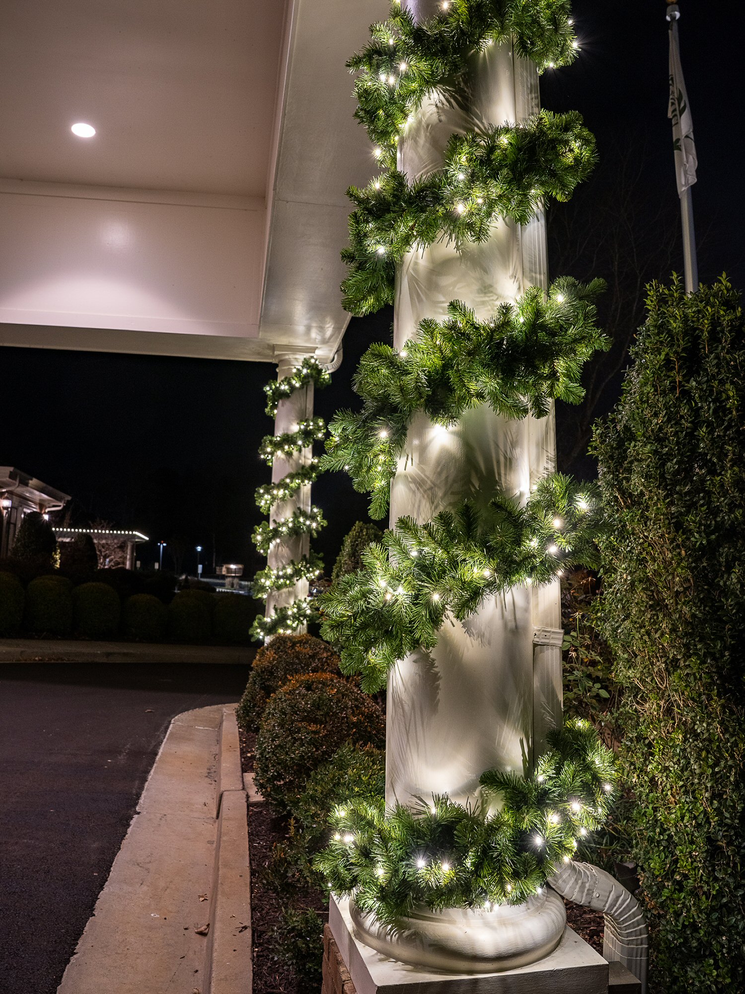 Lighted holiday garland wrapped around columns at a commercial property
