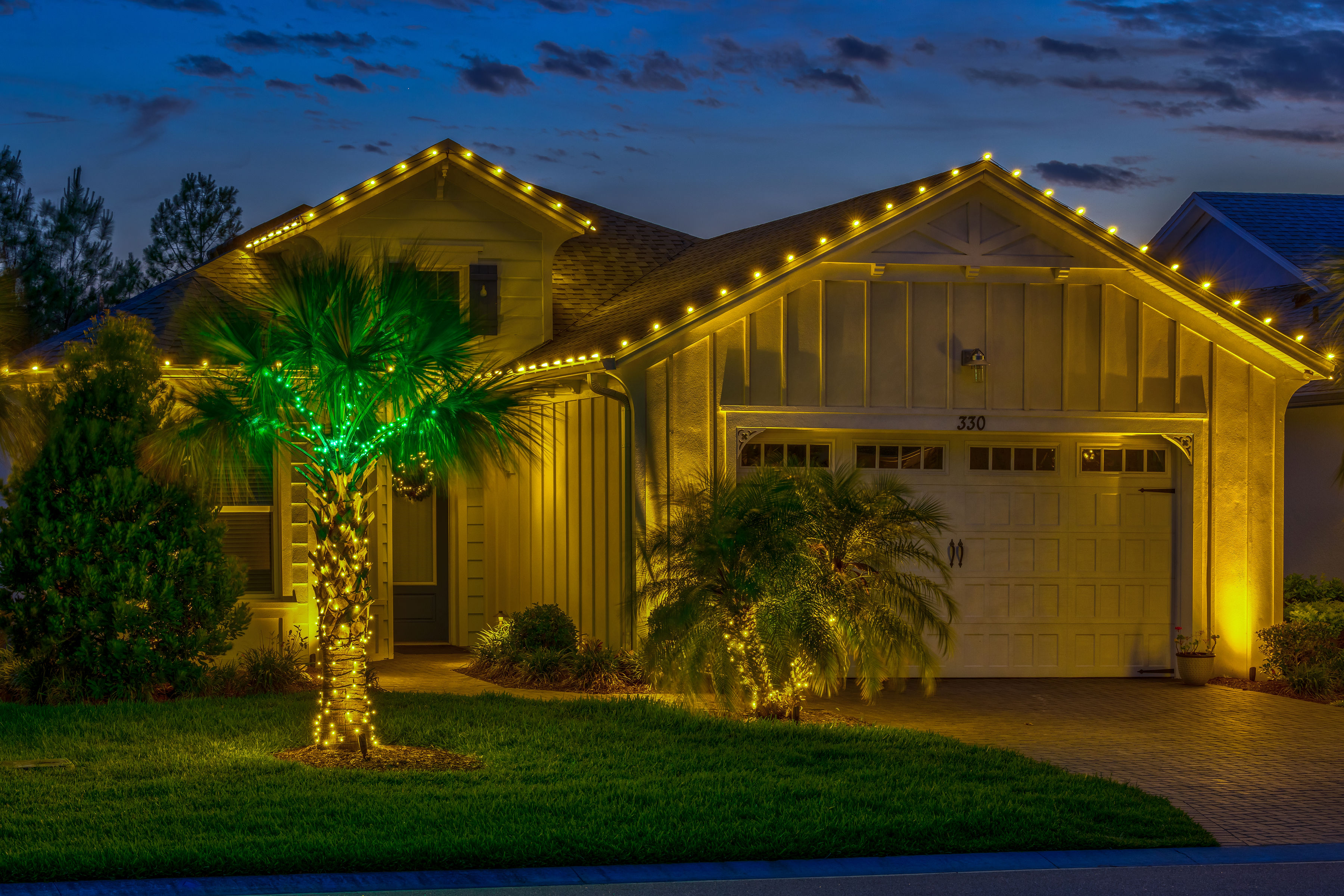 holiday lighting on house and palm trees