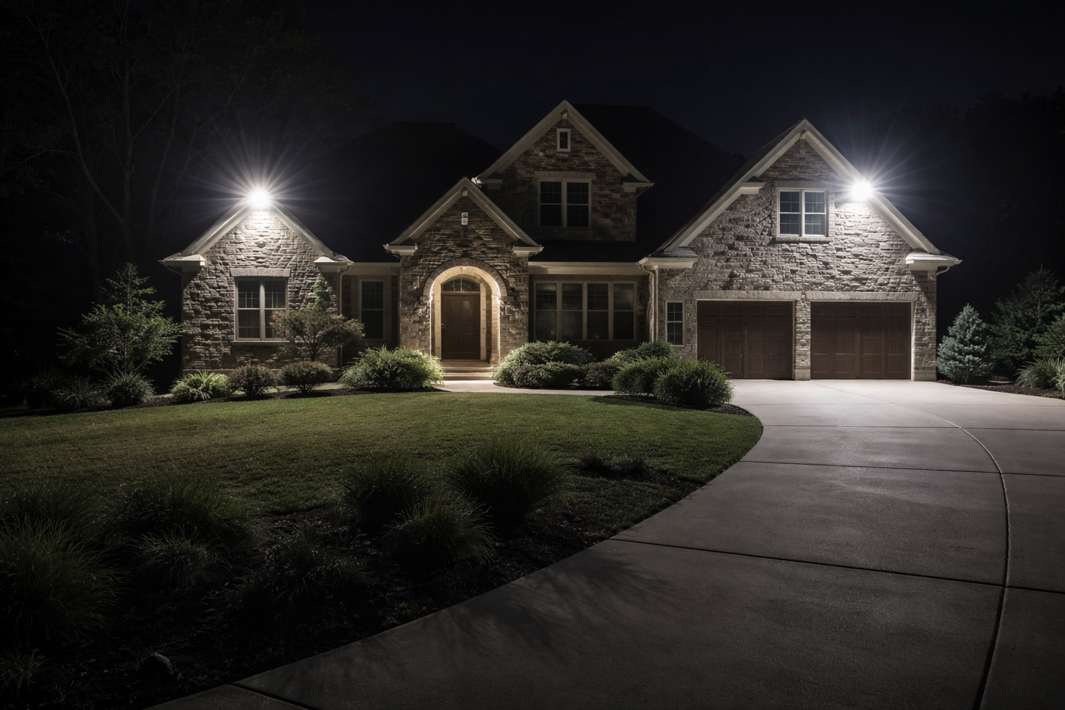 Front walkway of a large home at dusk illuminated with professional outdoor lighting, including path lights, landscape lighting, and soft architectural lighting on the porch and façade.